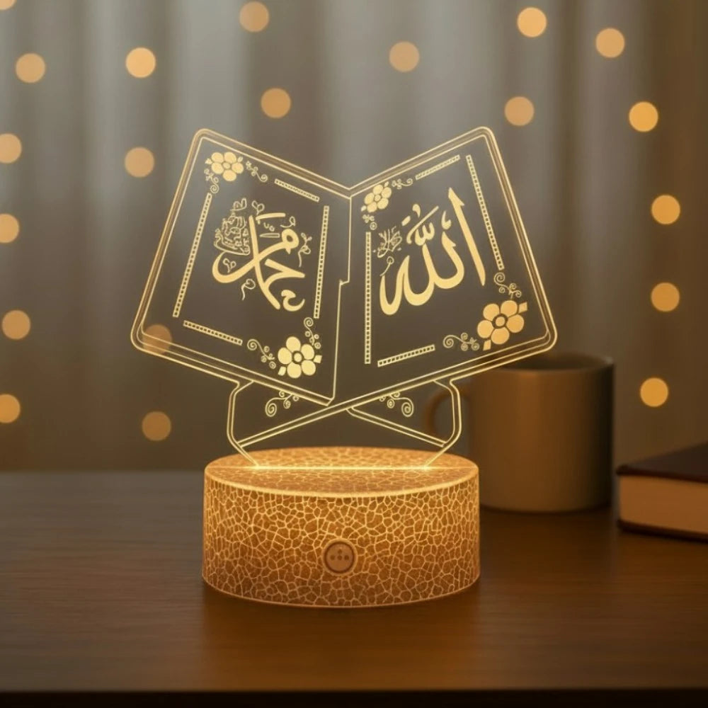 Veilleuse LED Coranique Booka en forme de livre ouvert, gravures "Allah" et "Muhammad" illuminées en doré, posée sur une commode en bois avec guirlande lumineuse en arrière-plan