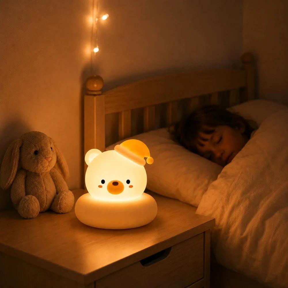 Veilleuse LED ours Bouba diffusant une lumière chaude sur une table de chevet dans une chambre d’enfant