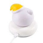 Veilleuse LED ours Bouba blanche avec bonnet jaune, vue de dos avec câble USB branché sur le socle