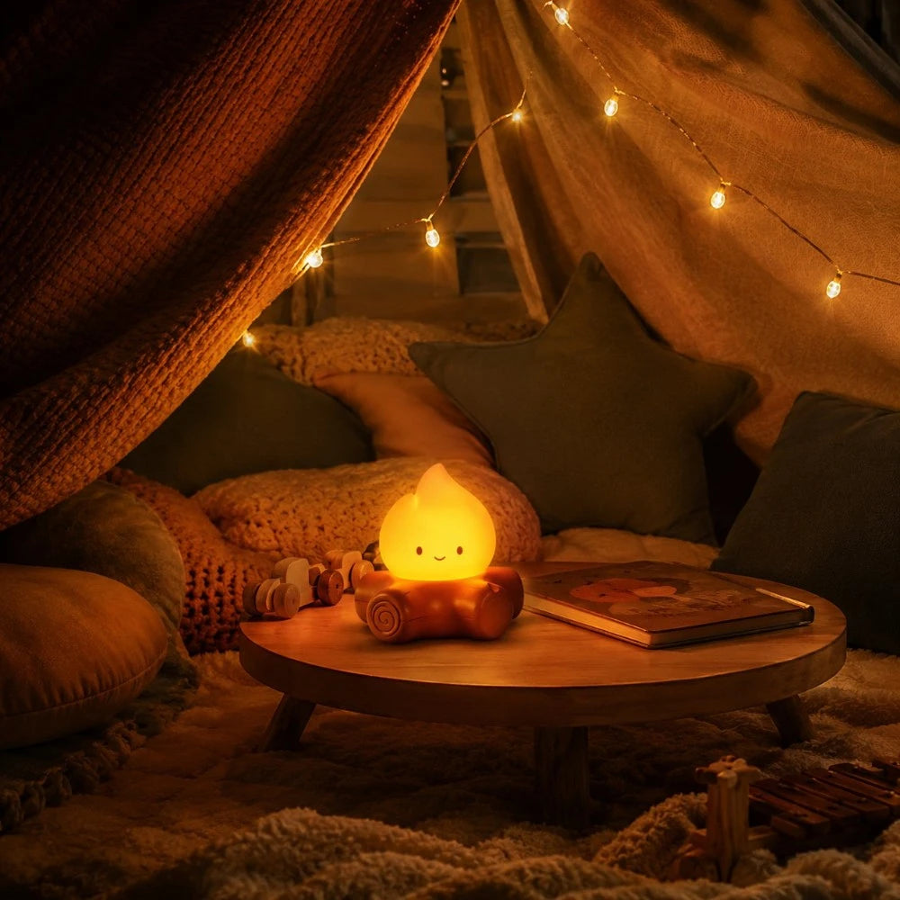 Veilleuse LED Braise allumée dans une cabane cocooning avec coussins et guirlande lumineuse