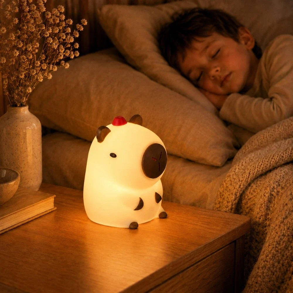 Veilleuse LED capybara Capy allumée sur une table de chevet près d'un enfant endormi