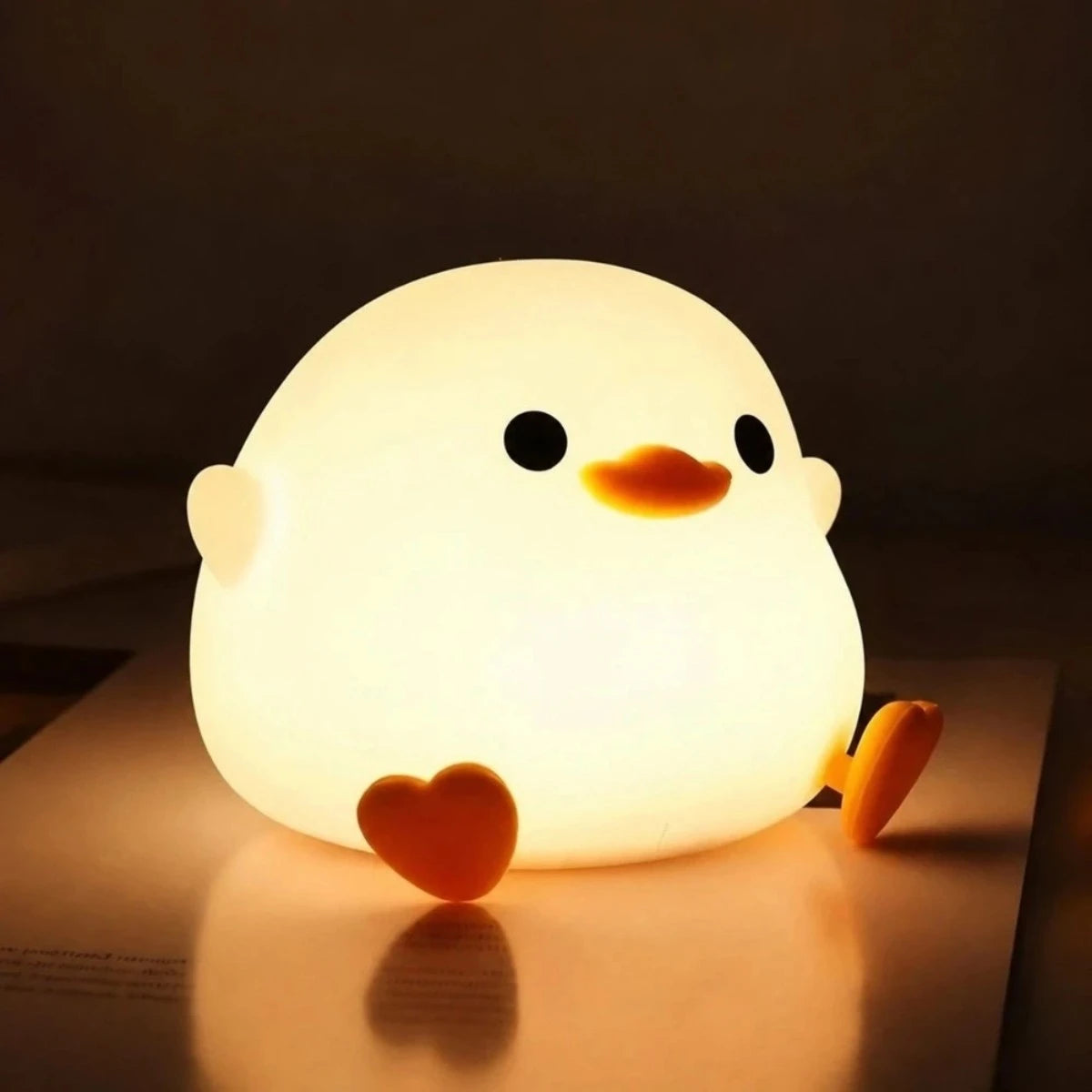 Veilleuse Kiki en forme de caneton, lumière chaude, posée sur une table dans une ambiance douce.