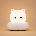 Veilleuse LED chat blanche Mimo allumée, avec oreilles roses et socle arrondi, sur fond beige clair.