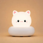 Veilleuse LED chat blanche Mimo allumée, avec oreilles roses et socle arrondi, sur fond beige clair.