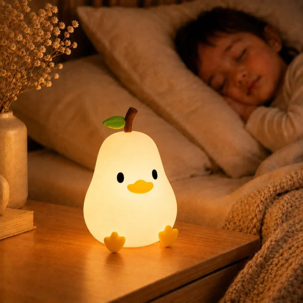 Veilleuse LED canard-poire Willy allumée sur une table de chevet près d'un enfant endormi