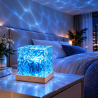 Veilleuse Aqua en lumière bleue sur une table de chevet, projetant des reflets d'eau ondulants sur le mur et le plafond d'une chambre