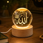 Gros plan lampe cristal LED Serenita gravée Allah sur socle bois, câble USB visible, ambiance chaleureuse